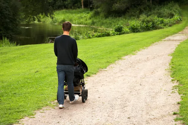 A man walking with a stroler in a park. Mostphotos.