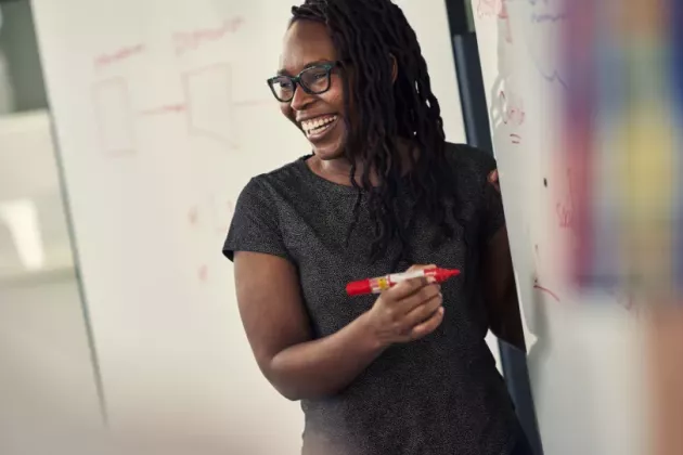 A woman in front of a whiteboard.